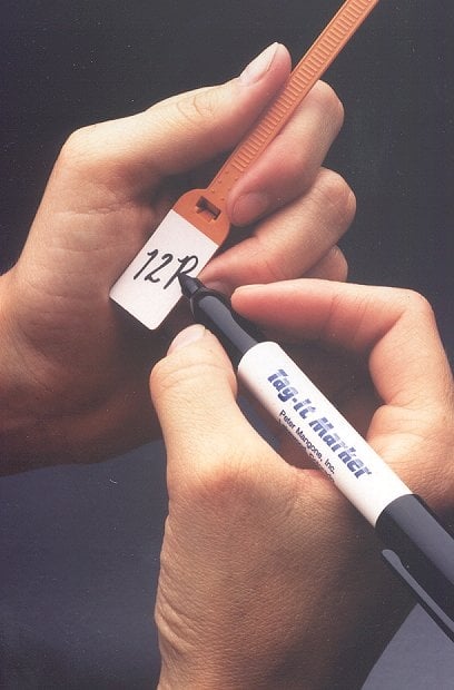 Hand holding two labeled cables or cords against a dark background.
