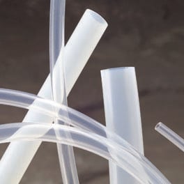 White ribbon bows tied around clear cylindrical objects against a gray background.