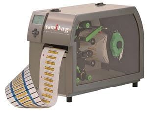 Portable label maker with tan and green color scheme and roll of adhesive labels.