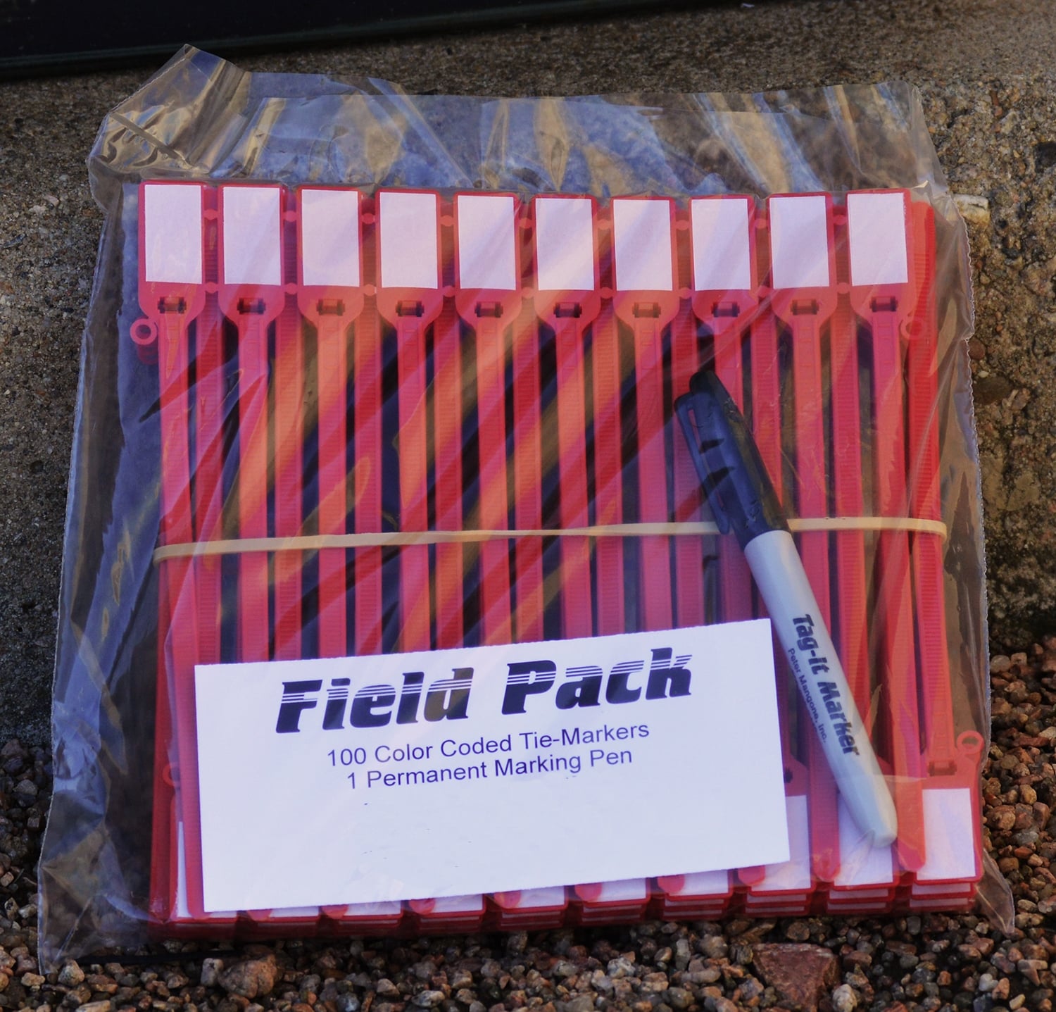Field Pack containing 100 color-coded tie-markers and one permanent marking pen on gravel surface.