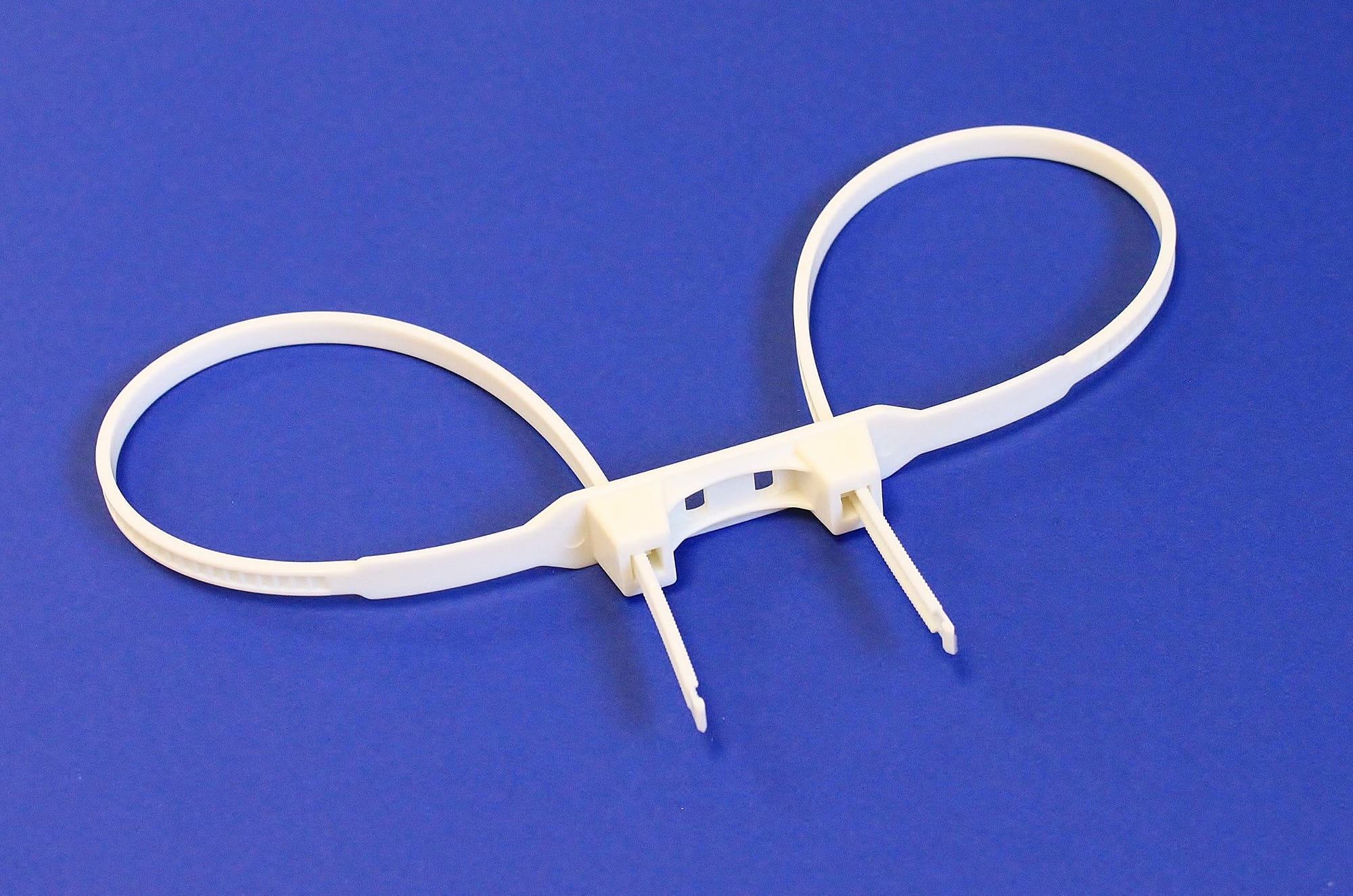 White cable ties arranged in a figure-eight pattern on a blue background.