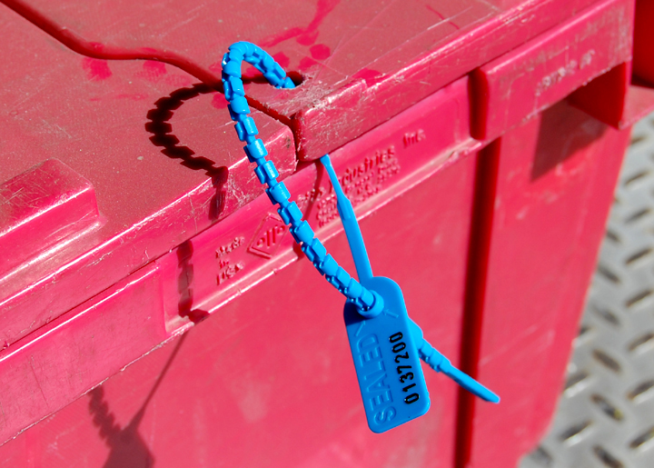 Blue plastic zip tie securing a black cable to a bright pink plastic crate.