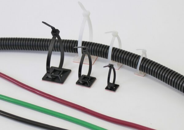 Cable ties securing a black corrugated tube and colored wires to a white surface.