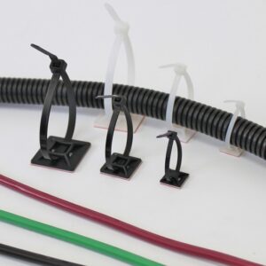 Cable ties securing a black corrugated tube with colored wires below on a white surface.