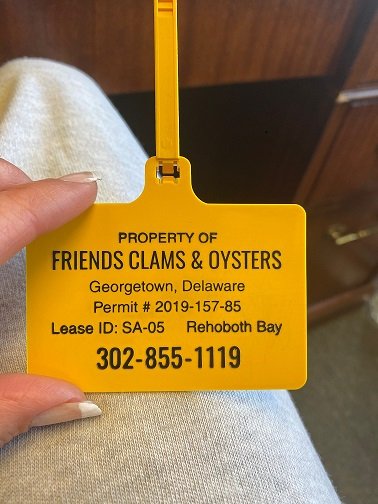 Yellow property tag for Friends Clams & Oysters in Georgetown, Delaware with lease and contact.