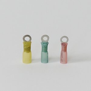 Three cylindrical wire connectors in yellow, green, and pink with metal loops on top.