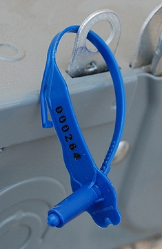Blue plastic bottle holder with clear top clip attached to white surface.