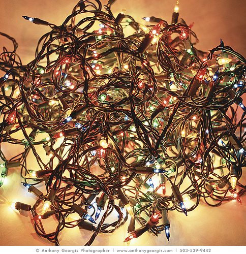 Tangled string of warm white and multicolored Christmas lights on a beige background.
