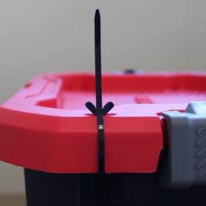 Black cable tie securing a red and black plastic container.